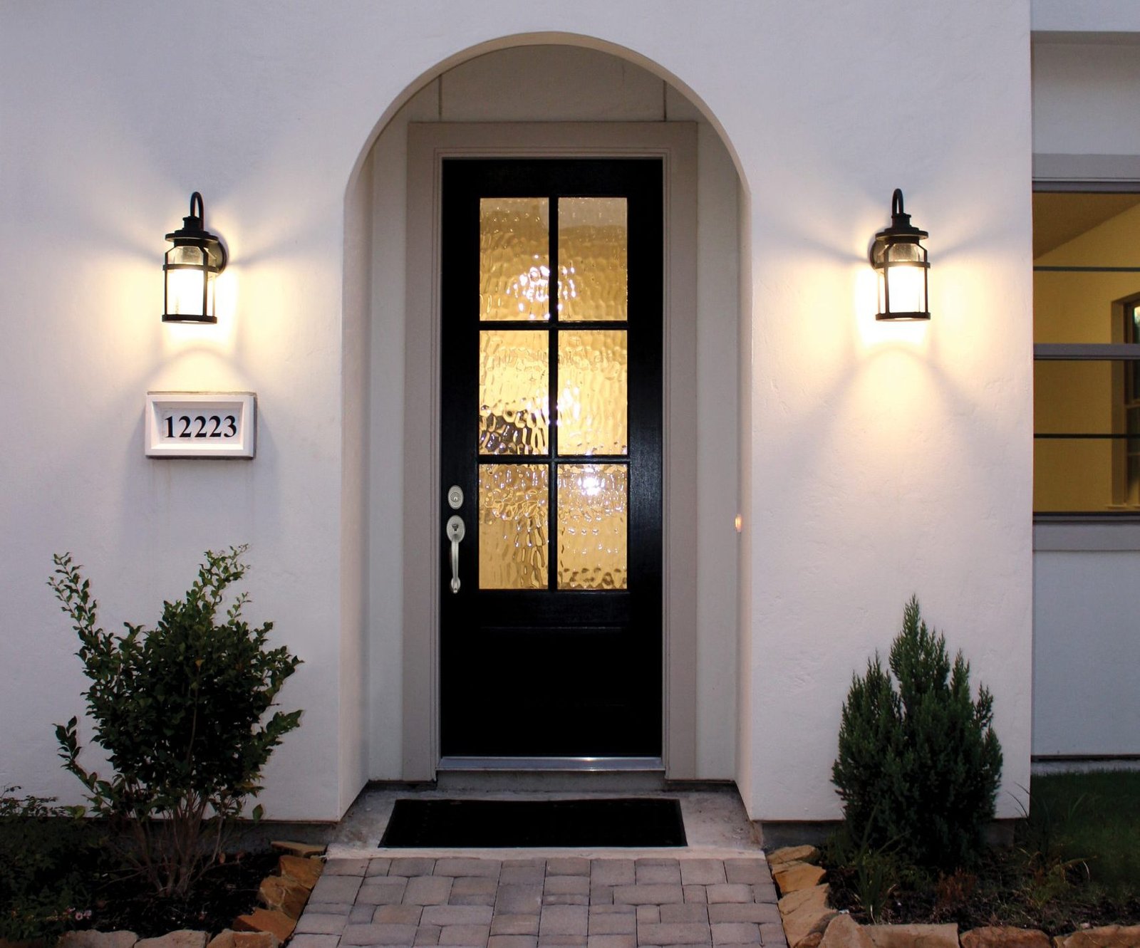 white stucco home with black woodcraft entry door in archway entrace